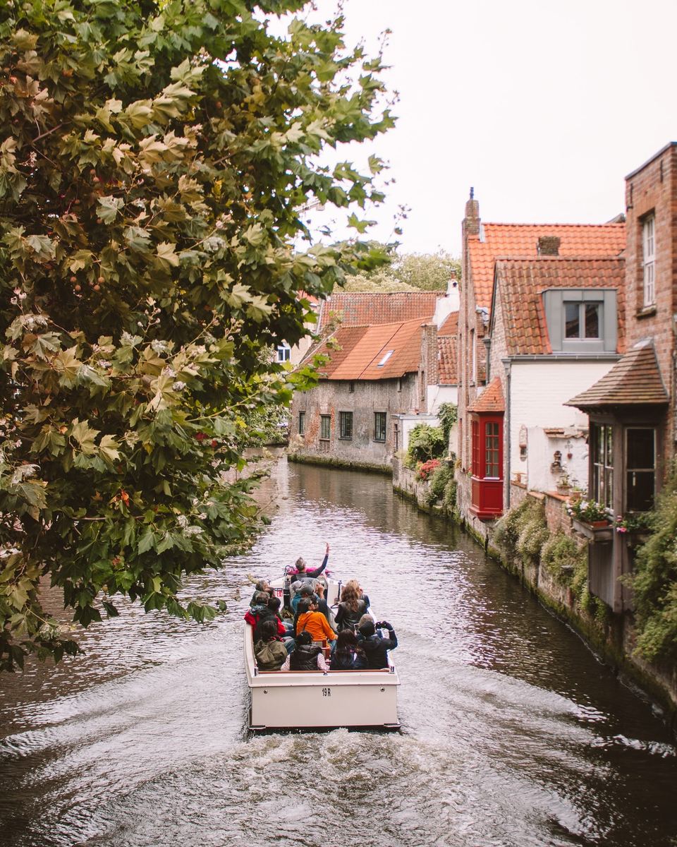 Tourist boat on a leafy Bruges canal